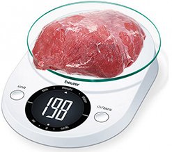 weighing raw dog meat on a scale to prepare the right amount for a daily puppy meal